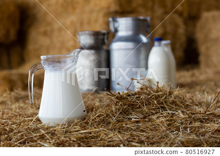 Jug, cans and glass with milk on hay stacks Jug, cans and glass with milk on hay stacks 80516927
