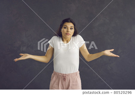 Clueless young woman with an indifferent face expression shrugging her shoulders 80520296
