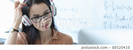 Teacher with headphones on his head looking at laptop screen 80520410