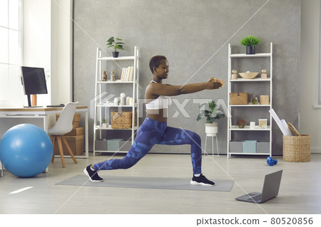 Happy young woman doing sports exercises with online video workout lesson at home Happy young woman doing sports exercises with online video workout lesson at home 80520856