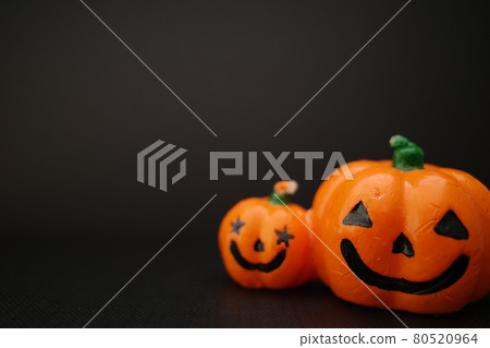 Two smiling orange pumpkin candles side by side 80520964