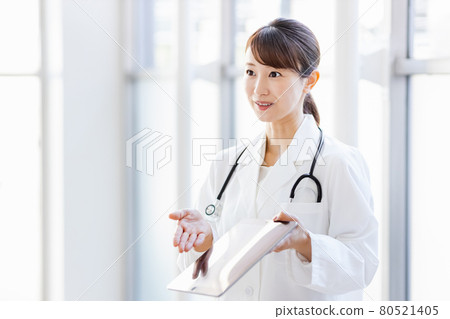 A female doctor showing the screen of a tablet device to a person outside the frame A female doctor showing the screen of a tablet device to a person outside the frame 80521405