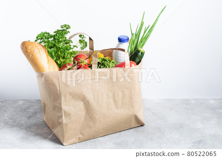 Paper shopping box full of fresh organic vegetables and grocery products on grey table. 80522065