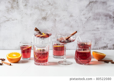 Glasses of mulled wine, orange slices, cinnamon and anise stars on white background with shadows. 80522080