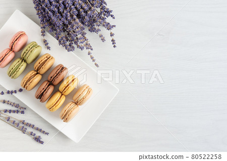 Multi colored french macaroons in a box top view on white wooden background. 80522258