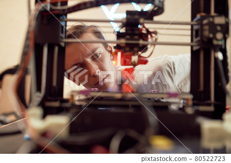 Young male looking at 3D printer Young male looking at 3D printer 80522723