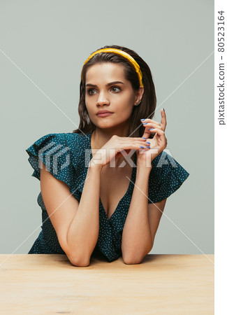 Half-length portrait of young girl in retro style, fashion of 70s, 80s years isolated on gray studio background with copyspace for ad. 80523164
