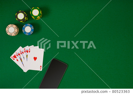 different color chips for gamblings and playing cards on green different color chips for gamblings and playing cards on green 80523363