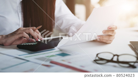 Close up of businesswoman or accountant using calculator to calculate business data, accountancy document and laptop computer at office, business financial concept. Close up of businesswoman or accountant using calculator to calculate business data, accountancy document and laptop computer at office, business financial concept. 80524023