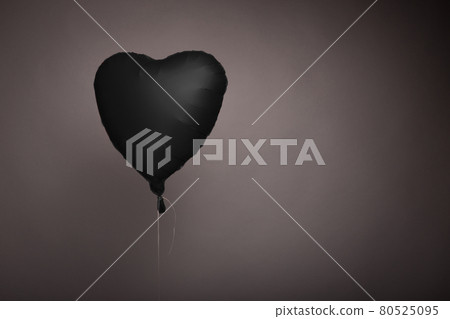 black ball in the form of a heart on a gray background in the studio 80525095