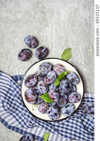 Ripe blue plums on a plate Ripe blue plums on a plate 80525137