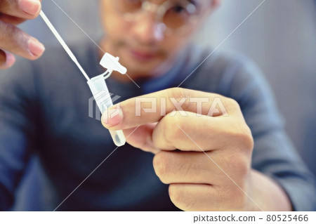 Man uses cotton swab to test for Covid-19 Insert a reagent bottle to look for what is believed to be a virus. 80525466