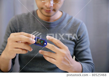 Man measuring his own oxygen   Using a Fingertip Pulse Oximeter. 80525468