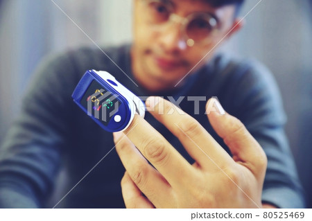 Man measuring his own oxygen Using a Fingertip Pulse Oximeter. Man measuring his own oxygen Using a Fingertip Pulse Oximeter. 80525469