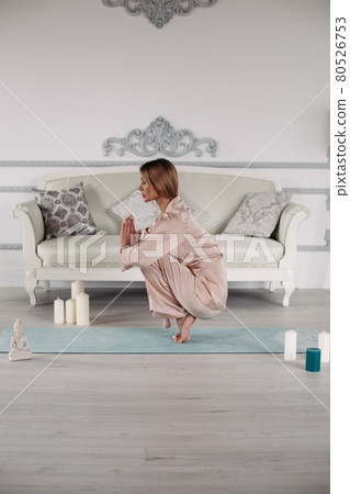 Young lady practicing yoga at home on exercise mat 80526753