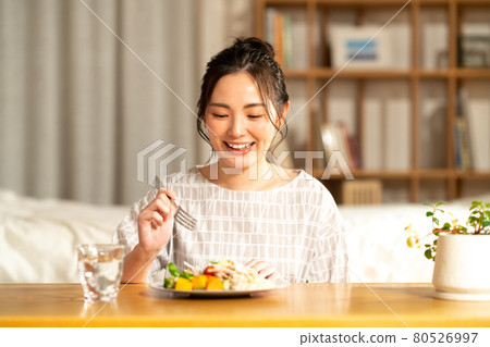 A young woman eating dinner A young woman eating dinner 80526997