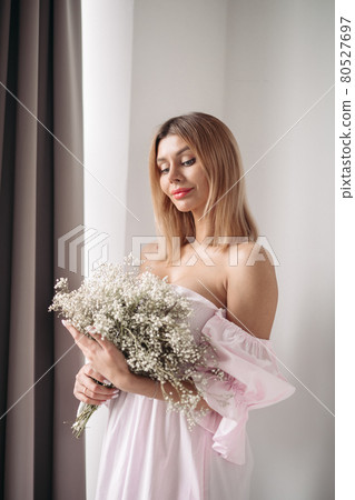 Pretty smiling young woman standing with a bouquet Pretty smiling young woman standing with a bouquet 80527697