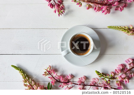 coffee cup with saucer and pink lupine flowers on board white wooden background. Place for your text and product, copy space, top view, flatlay. 80528516