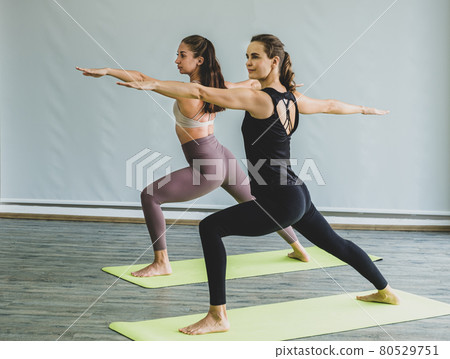 Two Caucasian women exercise doing the yoga pose stretching at home, healthy lifestyle concept Two Caucasian women exercise doing the yoga pose stretching at home, healthy lifestyle concept 80529751