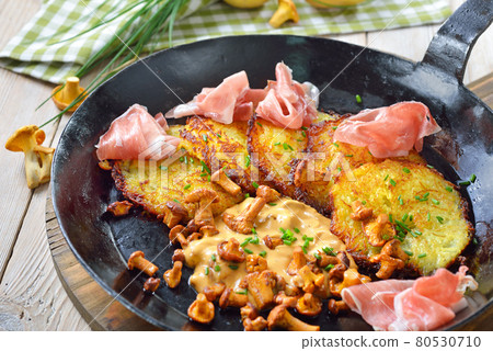 Crunchy potato pancakes with fresh chanterelles, cream sauce and hearty South Tyrolean bacon 80530710