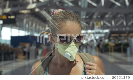 Woman caucasian at airport with wearing protective medical mask on head against the background of the plane. Coronavirus sars-cov-2 covid-19. Woman caucasian at airport with wearing protective medical mask on head against the background of the plane. Coronavirus sars-cov-2 covid-19. 80531379