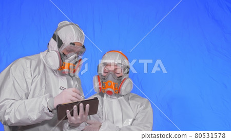 Scientist virologist in respirator makes write in an tablet computer with stylus. Man and woman wearing protective medical mask. Chroma key blue. 80531578