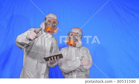 Scientist virologist in respirator makes write in an tablet computer with stylus. Man and woman wearing protective medical mask. Chroma key blue. 80531580