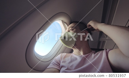 Man travel caucasian at plane with wearing protective medical mask. Male tourist at aircraft with protect respirator. Coronavirus covid-19. Man travel caucasian at plane with wearing protective medical mask. Male tourist at aircraft with protect respirator. Coronavirus covid-19. 80531937