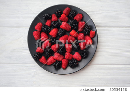 Fresh organic summer berries mix in round black table 80534158