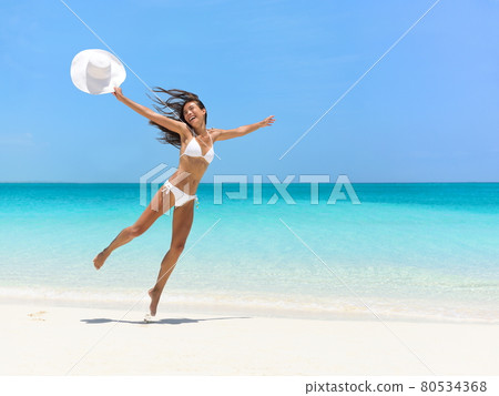 Carefree Woman Jumping At Beach During Summer 80534368