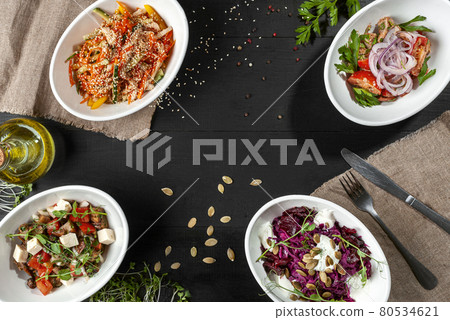 Salads of vegetables, greens, meat and cheese on black wooden background Salads of vegetables, greens, meat and cheese on black wooden background 80534621