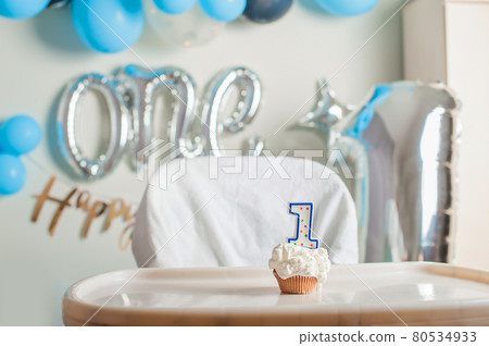 Yummy birthday cupcake with candle for first year of birth. Boy's anniversary table decor. Yummy birthday cupcake with candle for first year of birth. Boy's anniversary table decor. 80534933