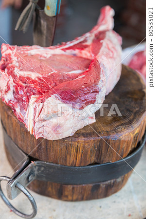 Raw meat on a deck, a knife stuck in the meat. Fresh meat on a cutting board. Raw meat on a deck, a knife stuck in the meat. Fresh meat on a cutting board. 80535021