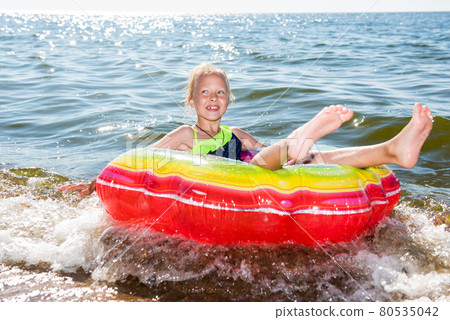 Portrait of little girl with inflatable rubber circle on beach 80535042