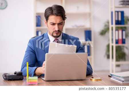 Young male employee sitting at workplace 80535177