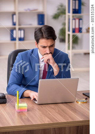 Young male employee sitting at workplace Young male employee sitting at workplace 80535184