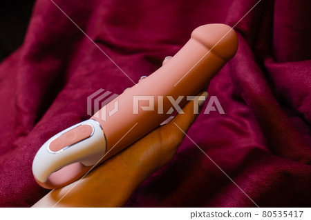 Woman in bedroom holding vibrator in hand. 80535417