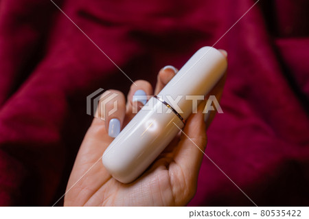 Woman in bedroom holding vibrator in hand. Woman in bedroom holding vibrator in hand. 80535422