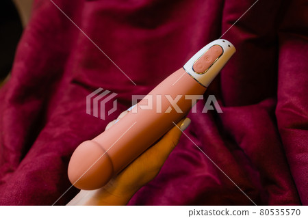Woman in bedroom holding vibrator in hand. 80535570