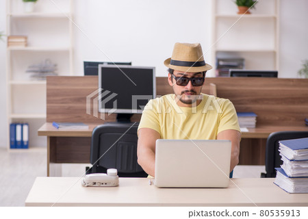 Young male employee preparing for trip at workplace Young male employee preparing for trip at workplace 80535913