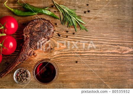 Barbecue dry aged rib of beef with vegetables and glass of red wine close-up on wooden background 80535932