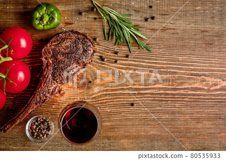 Barbecue dry aged rib of beef with vegetables and glass of red wine close-up on wooden background Barbecue dry aged rib of beef with vegetables and glass of red wine close-up on wooden background 80535933