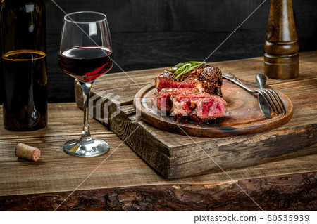Grilled ribeye beef steak with red wine, herbs and spices on wooden table Grilled ribeye beef steak with red wine, herbs and spices on wooden table 80535939