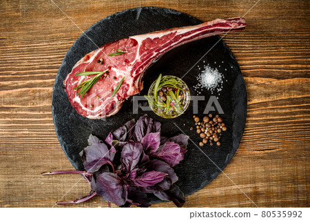Dry aged raw tomahawk beef steak with ingredients for grilling Dry aged raw tomahawk beef steak with ingredients for grilling 80535992