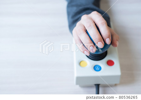 Woman with cerebral palsy works on a specialized computer mouse. 80536265