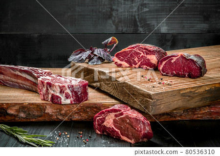Fresh raw beef on cutting board with fresh basil and a sprig of rosemary Fresh raw beef on cutting board with fresh basil and a sprig of rosemary 80536310
