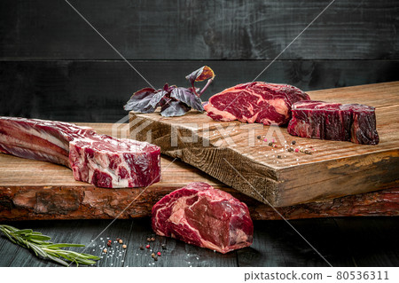 Fresh raw beef on cutting board with fresh basil and a sprig of rosemary Fresh raw beef on cutting board with fresh basil and a sprig of rosemary 80536311