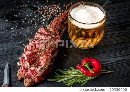 Grilled steak seasoned with spices and fresh herbs served with mug of beer, fresh red pepper 80536406