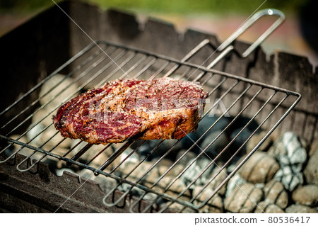 Hot spicy steak grilling on a summer barbecue over the hot coals garnished. 80536417