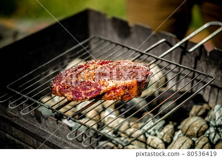 Hot spicy steak grilling on a summer barbecue over the hot coals garnished. Hot spicy steak grilling on a summer barbecue over the hot coals garnished. 80536419